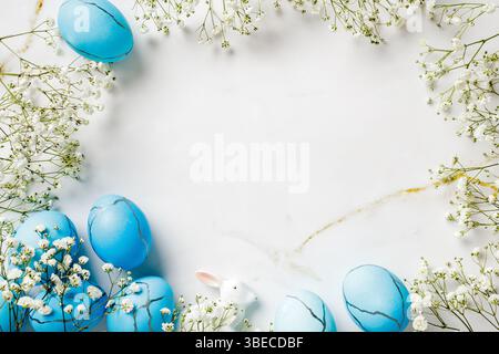 Easter scene with blue Easter eggs with flowers on marble table. Top view. Stock Photo