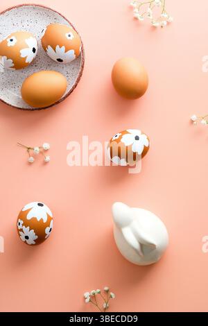 Happy Easter flat lay composition. Easter eggs, spring flowers, Easter bunny rabbit on pastel pink background. Minimal style. Stock Photo