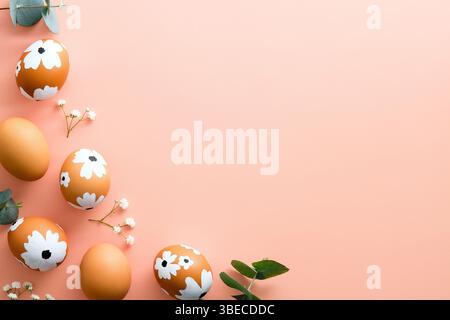 Happy Easter card. Frame made of Easter eggs and spring flowers on pastel pink background. Flat lay, top view, copy space. Stock Photo