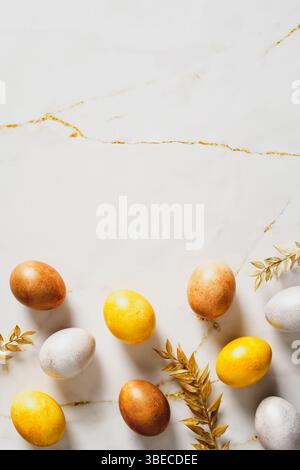 Luxury Easter vertical flat lay composition. Elegant Easter eggs with golden branches on marble table. Stock Photo