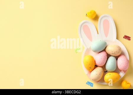 Happy Easter banner template. Colorful Easter eggs on plate with bunny ears. Top view. Flat lay. Stock Photo