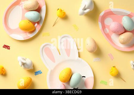 Happy Easter card. Easter eggs and table serving cutlery on yellow background. Flat lay, top view. Stock Photo