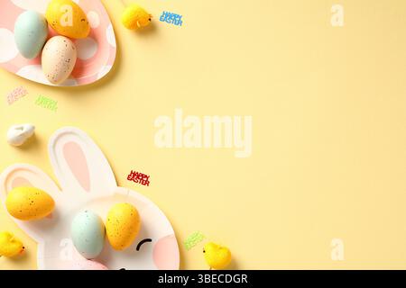 Happy Easter composition. Flat lay Easter eggs and table serving cutlery on yellow background. Stock Photo