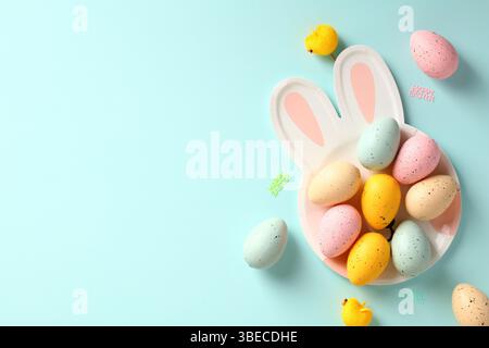 Easter rabbit shaped plate with colorful Easter eggs on blue background. Happy Easter greeting card template. Stock Photo