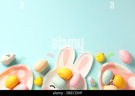 Happy Easter greeting card template. Frame border made of Easter eggs, plates, decoration on blue background. Stock Photo