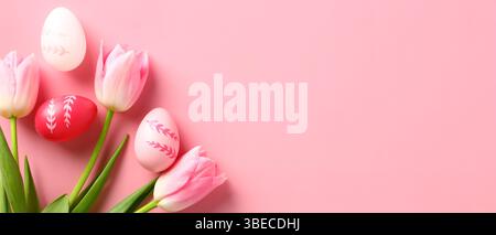 Happy Easter banner design. Tulips and Easter eggs on pastel pink background. Top view with copy space. Stock Photo
