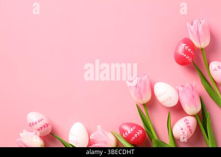 Happy Easter concept. Easter greeting card template with colorful Easter eggs and tulips on a pink background. Stock Photo