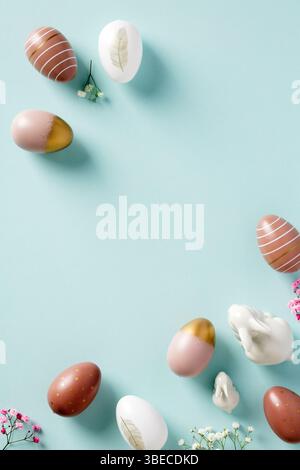 Happy Easter vertical banner design with colorful Easter eggs, bunnies, flowers on pastel blue table. Stock Photo
