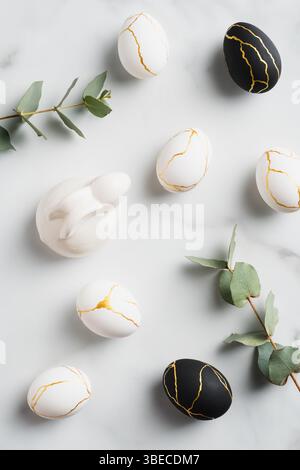 Easter flat lay composition with luxury easter eggs, bunny rabbit, eucalyptus leaves on marble background. Stock Photo