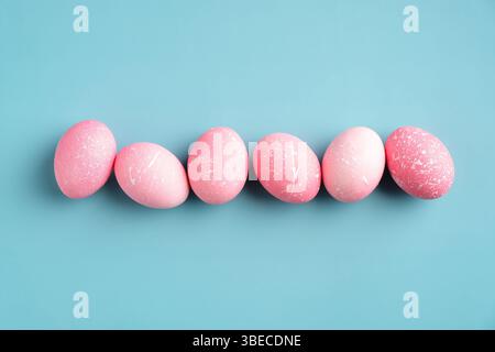 Row of pink Easter eggs on turquoise background. Happy Easter minimal concept. Flat lay, top view. Stock Photo