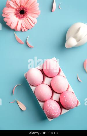Pink Easter eggs, bunny, spring flower, petals on turquoise background. Flat lay, top view, trendy colors. Stock Photo