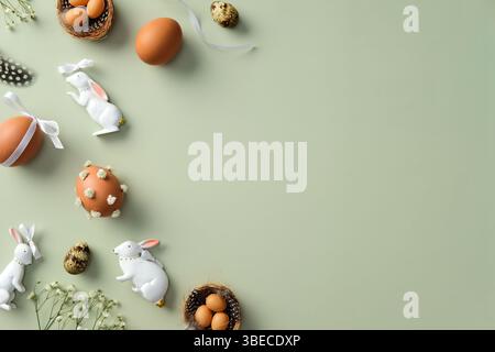 Happy Easter concept. Flat lay composition with Easter eggs, quail eggs, gypsophila flowers, Easter bunnies, feathers on pastel green background Stock Photo