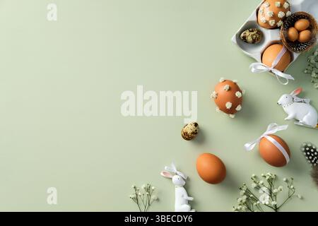 Flat lay composition with Easter eggs, ceramic bunnies, flower branches on pastel green background Stock Photo