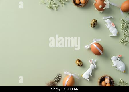 Happy Easter background. Flat lay composition with decorated Easter eggs, quail eggs, gypsophila flowers, Easter bunny, feathers on pastel green backd Stock Photo