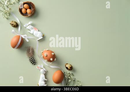 Happy Easter banner design. Top view green table with decorated Easter eggs, quail eggs, gypsophila flowers, Easter bunny, feathers Stock Photo