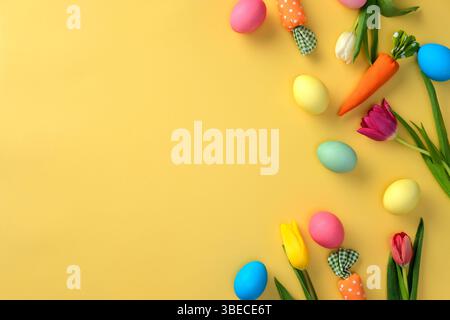 Flat lay colorful Easter eggs and spring flowers on a yellow background. Stock Photo
