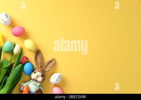 Happy Easter concept. Flat lay composition with colorful eggs, tulips and decorative Easter bunny Stock Photo