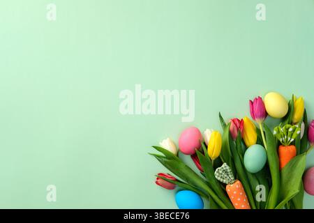 Happy Easter greeting card template with tulips, decorative carrots and colorful Easter eggs on green background Stock Photo