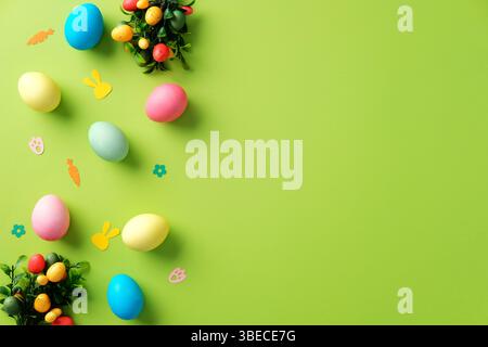 Happy Easter background with colorful Easter eggs and confetti on bright green table. Stock Photo