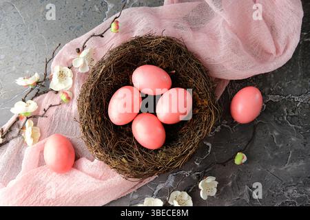 Pink Easter eggs in a nest surrounded by delicate white flowers on a marble surface. Perfect for springtime, Easter themes Stock Photo
