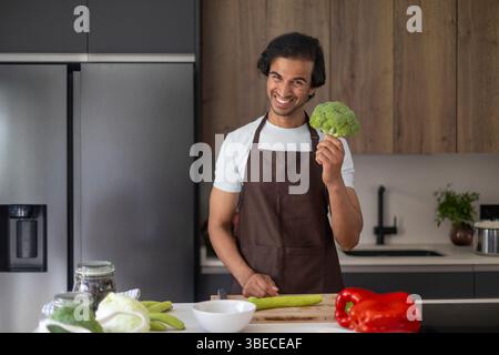 Chef holding fresh broccoli, preparing to cook in a stylish, modern kitchen. Stock Photo