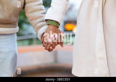 Close up of engaged couple holding hands showing off engagement ring while walking in the city Stock Photo