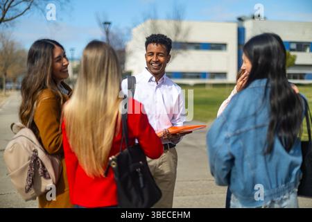 Happy teacher engaging with students on a university campus, holding a folder while fostering discussions and laughter in an academic setting Stock Photo