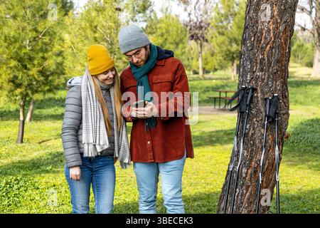 Hikers using smartphone app for checking trekking trail or browsing map during hiking day in the park Stock Photo