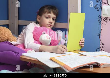 Girl in the evening does homework at home using a tablet computer Stock Photo