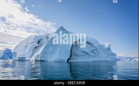 Large  iceberg with deep crevasse and dramatic sky in Disko Bay in Greenland Stock Photo