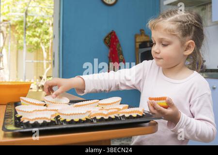 The child lays on a baking tins Easter cupcakes Stock Photo