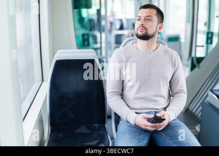 Bearded guy traveling in city bus and using mobile phone Stock Photo