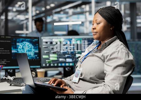 Data center admin using artificial intelligence neural networks node trees on laptop. Server room specialist using using AI programming language on notebook, configuring specialized hardware Stock Photo