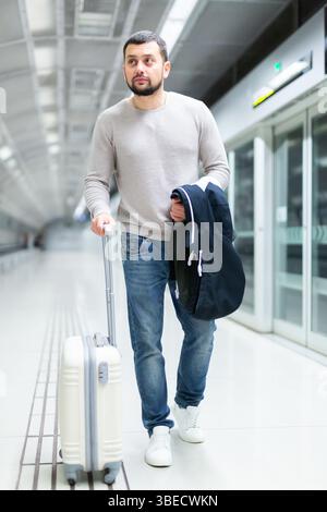 Young man walking through metro station with suitcase Stock Photo