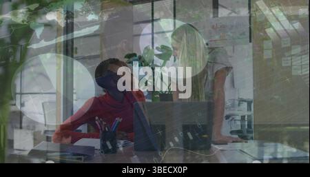 Statistical data processing against two diverse female office colleagues discussing at office Stock Photo