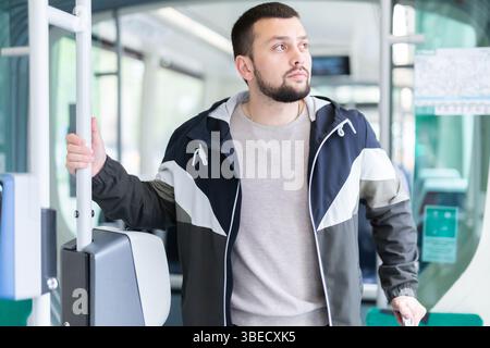 Young bearded man with suitcase riding in streetcar Stock Photo