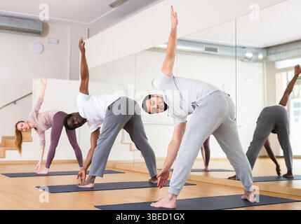 Young bearded man standing in twisting asana Parivrtta Prasarita Padottanasana Stock Photo