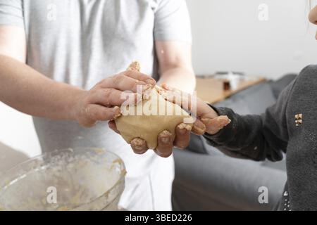 Close up view of the caucasian father helping to his child daughter adding and mixing ingredients in dough. Cropped view of the hands. Stock Photo