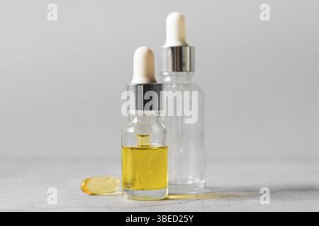 Glass dropper bottle with essential oil and omega capsule on grey background. Homeopathy concept. Stock Photo