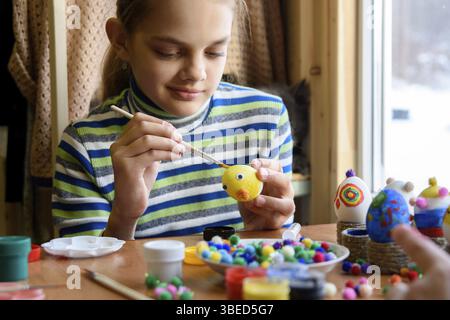 A twelve-year-old girl paints Easter eggs for the holiday Stock Photo