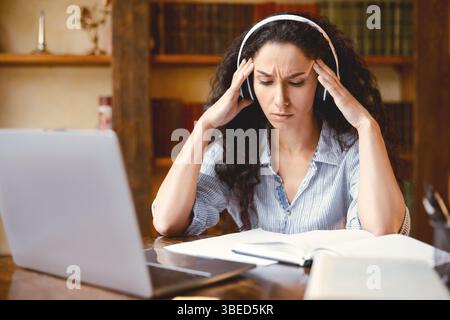 Tired woman massaging temples sitting at desk with laptop Stock Photo ...