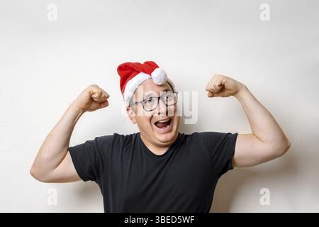 Happy funny strong young Santa man in red hat. December hoidays. Studio Stock Photo