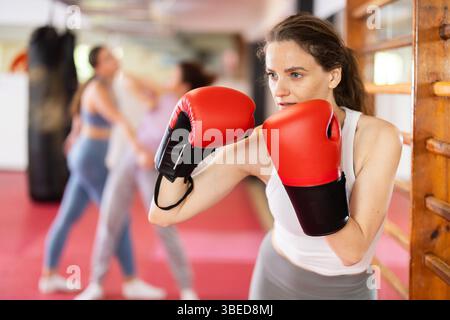 Woman practices punch with boxing gloves Stock Photo