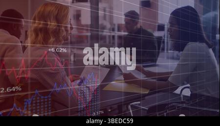 Statistical data processing against two diverse female office colleagues discussing at office Stock Photo