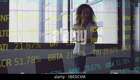 Image of stock market data processing over thoughtful african american woman at office Stock Photo