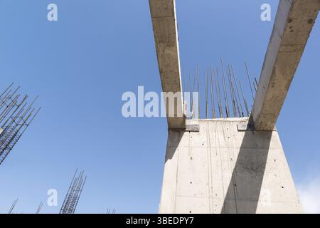 Concrete walls and columns in the in the building under construction, in a blue sky background. bottom view Stock Photo