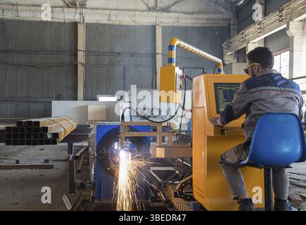 Worker sits behind a remote control gas welding machine. pipe cutting system Stock Photo
