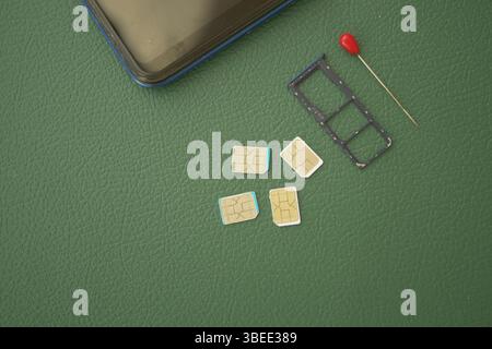 Multiple SIM cards and a tray placed on a green surface Stock Photo