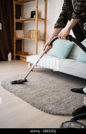 Cleaning concept. Man vacuuming carpet using vacuum cleaner, close-up Stock Photo