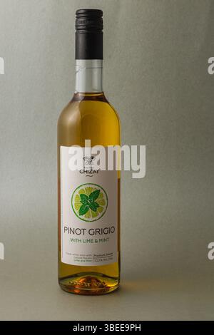 A bottle of pinot grigio featuring a refreshing lime and mint infusion stands against a simple backdrop, showcasing its vibrant color and appealing la Stock Photo
